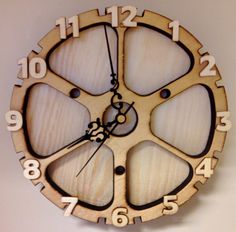 a clock made out of wood with numbers on the face and hands is hanging on a wall