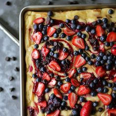 an uncooked dessert with strawberries and blueberries on top, ready to be eaten