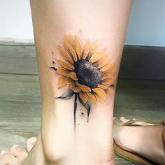 a woman's foot with a sunflower tattoo on the side of her leg