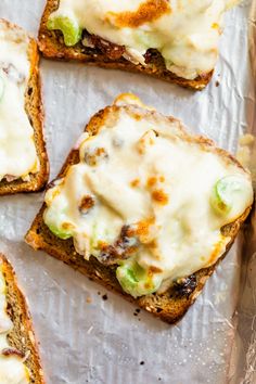 four pieces of bread with cheese and vegetables on top, sitting on foil lined up