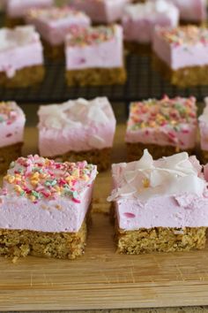 several pieces of cake with pink frosting and sprinkles on it sitting on a cutting board