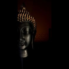 a black buddha head in the dark with gold beads on it's head and eyes