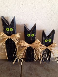 three black wooden cats with green eyes on them