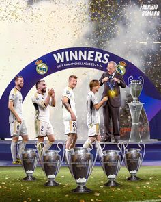 two men and three boys are standing in front of the trophies on stage with confetti falling around them