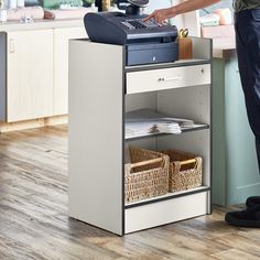 a person standing in front of a counter with a phone on it and baskets under the counter