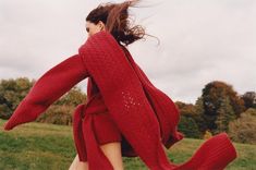 a woman in a red sweater is running through the grass