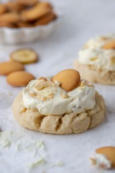 cookies with white frosting and orange peels are on the table next to other cookies