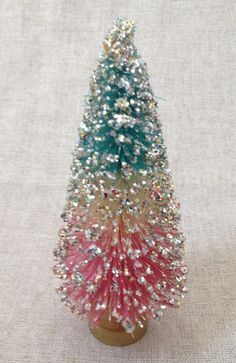 a small christmas tree is sitting on a white cloth covered tablecloth with sequins