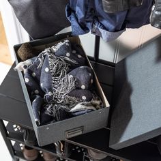 an open box filled with scarves on top of a black table next to a pair of shoes