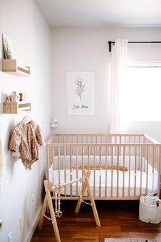 a baby's room with a white crib and wooden flooring in it