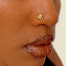 a woman's nose has a small sun piercing on it, as well as her lip