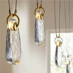 three glass vases hanging from the ceiling in a room with white walls and windows