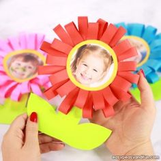 a person holding up a paper flower with two pictures on the top and one in the middle