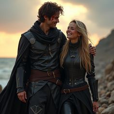 a man and woman dressed in medieval costumes standing next to each other on the beach