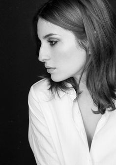 a black and white photo of a woman with long hair wearing a collared shirt