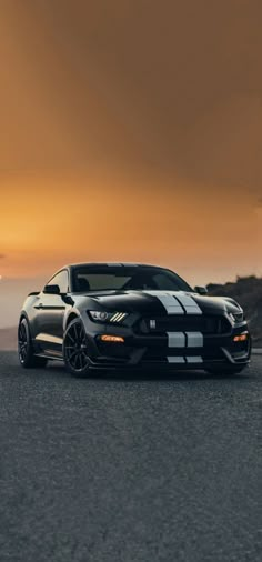 a black and white sports car parked on the side of the road at sunset or dawn