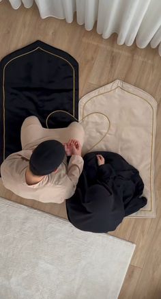 a person laying on the floor next to a black bag and white rug with gold trimmings