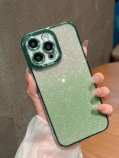 a person holding up a green phone case with glitter on the back and two black buttons