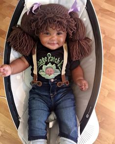 a small child with curly hair sitting in a stroller