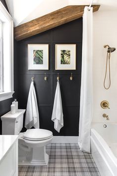 a white toilet sitting next to a bath tub in a bathroom under a wooden beam