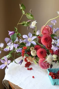 a vase filled with lots of flowers on top of a white tablecloth covered table