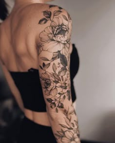 a woman's arm with flowers and leaves on the top half of her sleeve