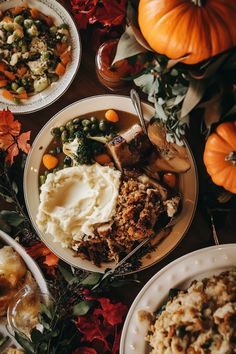 a table topped with plates of food next to pumpkins