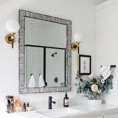 a bathroom with two sinks and a large mirror above the sink is decorated in black and white