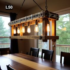 a light fixture hanging over a wooden table with black chairs and windows in the background