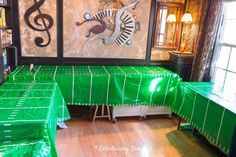 a room with tables covered in green cloths and musical notes on the wall behind them