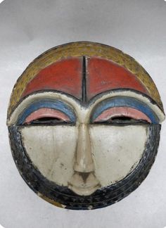 a white and red mask with two faces on it's face, against a gray background