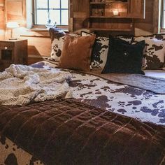 a bed with pillows and blankets on it in a room that has wood paneled walls