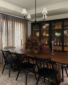 the dining room table is surrounded by black chairs and wooden shelves with candles on them