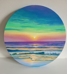 a painting of a sunset over the ocean on a round wall hanging ornament