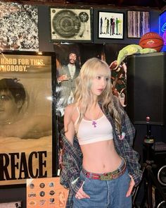 a young woman standing in front of a wall with posters on it's sides