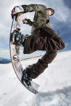 a snowboarder doing a trick in the air with his board on top of it