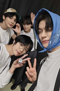 four young men posing for the camera with one holding his hand up in front of him