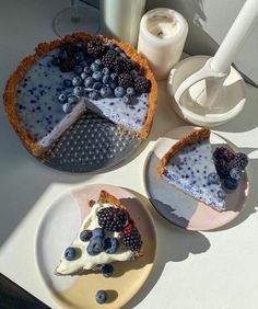 three pies with berries and blueberries on them sitting on plates next to milk