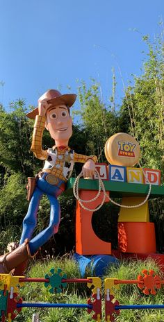 a large toy woody the cowboy is on display in front of some trees and bushes