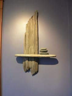 a piece of driftwood is mounted to the wall with two stacked rocks on it