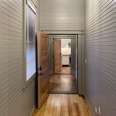 an empty hallway with wooden floors and two doors leading to another room in the house