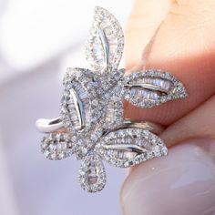 a woman's hand holding a diamond flower ring