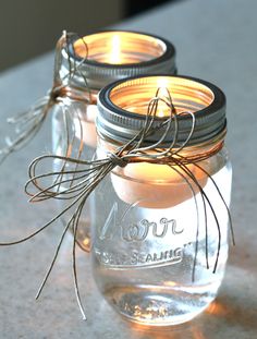 two mason jars filled with candles sitting on top of a countertop next to each other