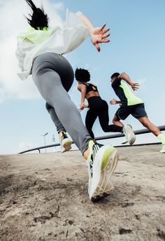 three people are running in the dirt on a sunny day with their feet spread out