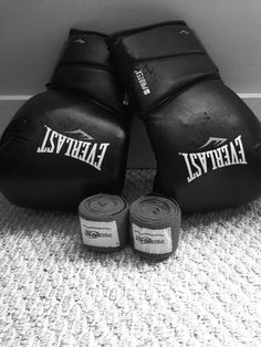 two black boxing gloves sitting on top of a carpet