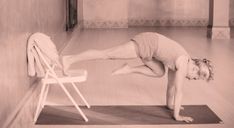 a woman is doing yoga on a mat in the middle of a room with chairs