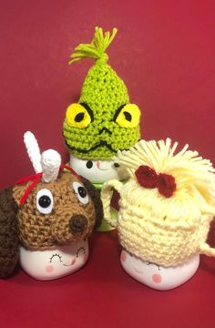 three crocheted stuffed animals sitting next to each other on a red table top