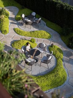 a person sitting at a table in the middle of a garden with grass growing around it