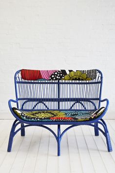 a blue bench sitting on top of a wooden floor next to a white brick wall