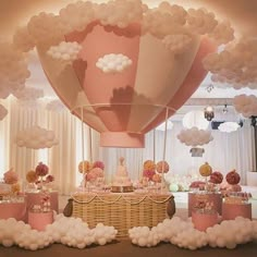 a large balloon filled with lots of white clouds floating over a table covered in cake